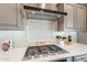 Close-up of kitchen stove and range hood, with tile backsplash at 623 E Peach Tree St, Queen Creek, AZ 85140