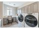 The laundry room has modern front-load machines with cabinetry, and a dedicated seating area for added convenience at 623 E Peach Tree St, Queen Creek, AZ 85140