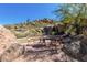 Desert oasis patio with dining table set among the rocks and lush vegetation, perfect for outdoor entertaining at 7411 E Quien Sabe Way, Scottsdale, AZ 85266