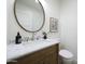 Bathroom vanity featuring marble counters, a dark wood cabinet, a round mirror, and modern fixtures at 7801 N 4Th Pl, Phoenix, AZ 85020