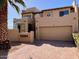A two-story stucco home features a two-car garage, red brick driveway, and lush desert landscaping at 7955 E Chaparral Rd # 34, Scottsdale, AZ 85250