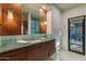 Bright bathroom featuring a large mirror, vanity with green marble countertop, and a glass-enclosed shower at 8724 N 68Th St, Paradise Valley, AZ 85253