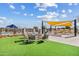 Community fire pit area with comfortable seating, lush landscaping, and an outdoor kitchen in the background at 10431 E Tiger Lily Ave, Mesa, AZ 85212