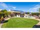 Expansive backyard featuring a well-manicured lawn, a refreshing pool, and solar panels on the roof at 15385 W Indianola Ave, Goodyear, AZ 85395