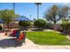 Charming backyard with a cozy seating area, lush green lawn, and mature trees for privacy at 15385 W Indianola Ave, Goodyear, AZ 85395