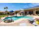 Relaxing pool area with rock features, seating, lush landscaping and outdoor bar area under a pergola at 15385 W Indianola Ave, Goodyear, AZ 85395