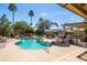 Relaxing pool area with patio, outdoor kitchen and bar, lush landscaping and seating areas in a private yard at 15385 W Indianola Ave, Goodyear, AZ 85395