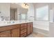 Bathroom showcases double sinks, wooden cabinetry, a soaking tub, and a shower with glass door at 17743 W Verdin Rd, Goodyear, AZ 85338