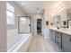 This bathroom features double sinks, granite countertops, grey shaker cabinets, a tub, and a glass shower at 17893 W Indigo Brush Rd, Goodyear, AZ 85338