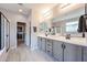 This bathroom features double sinks, granite countertops, grey shaker cabinets, and a glass shower at 17893 W Indigo Brush Rd, Goodyear, AZ 85338