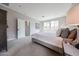 This bedroom features a king bed with white bedding, grey carpet, and a view of backyard through the three windows at 17893 W Indigo Brush Rd, Goodyear, AZ 85338