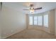 Cozy bedroom with plush carpeting, ceiling fan, and plantation shutters for privacy and comfort at 2433 E Hancock Trl, Casa Grande, AZ 85194