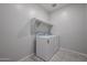 A laundry room features a washer, a dryer, tile floor, and a shelf at 35295 W La Paz St, Maricopa, AZ 85138