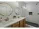 Modern bathroom with double sinks, wood cabinets, and glass-enclosed shower with herringbone tile at 4132 E Santa Fe Ln, Gilbert, AZ 85297