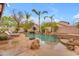 Backyard oasis with pool, spa, and waterfall feature, surrounded by palm trees at 5615 W Tonopah Dr, Glendale, AZ 85308