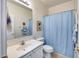 Clean bathroom featuring a vanity with a sink, toilet, and shower with a blue curtain at 7317 W Southgate Ave, Phoenix, AZ 85043