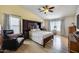 Relaxing bedroom with reading chair, light wood floors, and a ceiling fan at 7317 W Southgate Ave, Phoenix, AZ 85043