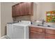 Well-lit laundry room with washer, dryer, sink, and ample cabinet storage space at 857 S Osborn Ln, Gilbert, AZ 85296