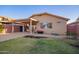 Spacious backyard with a covered patio, grassy area, gravel, and exterior view of the tan home at 1010 E Vernoa St, San Tan Valley, AZ 85140