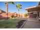 Large backyard featuring brick-paved and gravel areas, a grassy lawn, and mature palm trees at 1010 E Vernoa St, San Tan Valley, AZ 85140