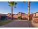 Cozy backyard featuring a brick-paved area, gravel, a grassy area, palm trees, and a vibrant red brick wall at 1010 E Vernoa St, San Tan Valley, AZ 85140