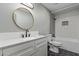 Modern bathroom features a stylish vanity, round mirror, and tiled shower-tub combination at 15868 N 18Th N Pl, Phoenix, AZ 85022