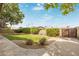 Grassy backyard with a concrete border, mature trees, and a gate, perfect for outdoor activities at 2110 E Laguna Dr, Tempe, AZ 85282