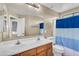 Bathroom with a double sink vanity, large mirror, and a shower with blue curtain at 24848 W Kowalsky Ln, Buckeye, AZ 85326