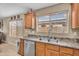 Bright kitchen with stainless steel dishwasher, tile backsplash, and dual windows for ample light at 24848 W Kowalsky Ln, Buckeye, AZ 85326