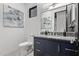 Modern bathroom with a blue vanity, granite counters, a toilet, and a large decorative painting at 29501 N 76Th St, Scottsdale, AZ 85266