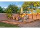 Backyard patio features a fire pit with ample seating, lush trees and manicured landscaping at 3482 E Cotton Ln, Gilbert, AZ 85234