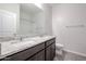 Bathroom featuring dark cabinets, granite countertops, double sinks, and a shower-tub combo at 35680 W Mallorca Ave, Maricopa, AZ 85138