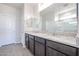 Bathroom featuring double sinks with granite countertops, dark wood cabinetry, and a large mirror at 35680 W Mallorca Ave, Maricopa, AZ 85138