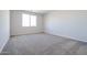 Empty carpeted bedroom with a large window and neutral paint at 35680 W Mallorca Ave, Maricopa, AZ 85138