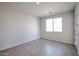 Bright bedroom features wood-style tile flooring, fresh paint, large window and white door at 35680 W Mallorca Ave, Maricopa, AZ 85138