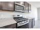 Close up of stainless steel gas range and microwave with granite countertops and wood cabinets at 35680 W Mallorca Ave, Maricopa, AZ 85138