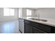 Close-up of kitchen island with stainless steel sink, faucet, dishwasher, and dark wood cabinets at 35680 W Mallorca Ave, Maricopa, AZ 85138