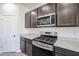 Modern kitchen features stainless steel stove, microwave, granite countertops, and dark wood cabinets at 35680 W Mallorca Ave, Maricopa, AZ 85138