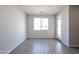 Bright living room with wood-style tile flooring, fresh paint, large window and white door at 35680 W Mallorca Ave, Maricopa, AZ 85138