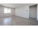 Bright, open living room with wood-look tile floors and neutral wall color at 35680 W Mallorca Ave, Maricopa, AZ 85138