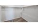 Empty walk-in closet with carpet flooring and wood clothing rods at 35680 W Mallorca Ave, Maricopa, AZ 85138