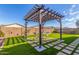 Lush backyard featuring a wooden pergola with string lights, a dining set, and green artificial turf at 40160 W Hensley Way, Maricopa, AZ 85138