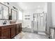 Bright bathroom featuring double sinks, a soaking tub, and a separate glass-enclosed shower for convenience at 40160 W Hensley Way, Maricopa, AZ 85138