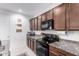 Well-equipped kitchen featuring granite countertops, black appliances, and ample cabinet space for storage at 40160 W Hensley Way, Maricopa, AZ 85138