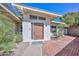 Close-up of the front entry, featuring a modern door, textured stucco, and a brick walkway, surrounded by greenery at 520 W Gibraltar Ln, Phoenix, AZ 85023