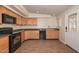 Kitchen featuring wood-look tile floors, wooden cabinets, granite countertops, and black appliances at 520 W Gibraltar Ln, Phoenix, AZ 85023