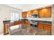 Traditional kitchen featuring wood cabinetry, granite countertops, and stainless steel appliances at 7910 W Adobe Dr, Glendale, AZ 85308