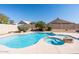 Sparkling swimming pool and spa surrounded by lush landscaping and a privacy wall at 7910 W Adobe Dr, Glendale, AZ 85308