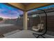 Covered patio features a hanging swing chair and a view of the backyard at dusk at 8005 S 69Th Ln, Laveen, AZ 85339