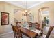 Formal dining room with a chandelier, arched doorway, and wrought iron stair case at 8432 S 21St Pl, Phoenix, AZ 85042